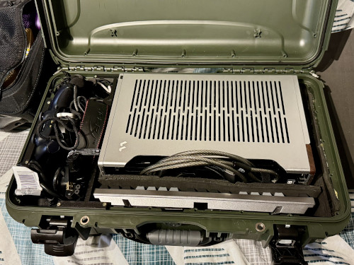 An open flight case, with the PC slotted in surrounded by foam. A keyboard sits below it, and various accessories on the side with 3D-printed supports.
