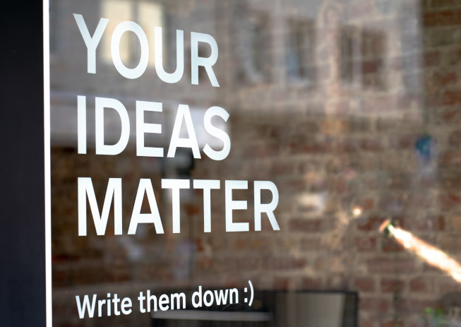 Photo of a sign reading "YOUR IDEAS MATTER … Write them down :)"