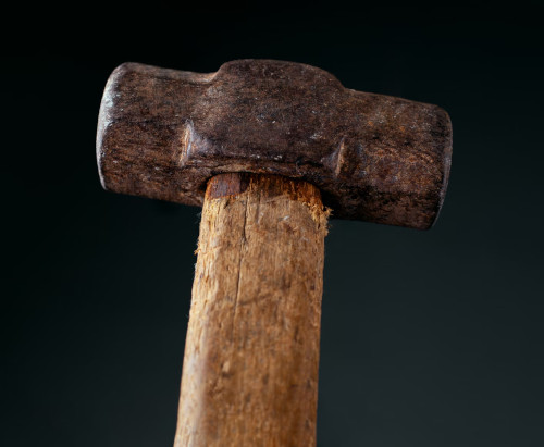 Closeup photo of a well-used hammer with a wooden handle